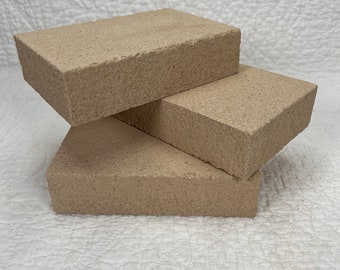 May include: Three beige rectangular blocks stacked on top of each other. The blocks are made of a porous material and have a rough texture.