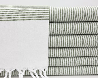 May include: A stack of white towels with green stripes. The towels have a fringe on the bottom.