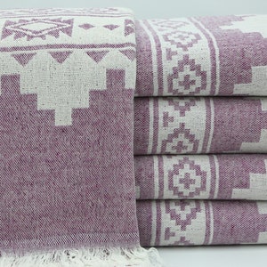 May include: A stack of purple and white patterned towels with fringe. The towels have a geometric design.