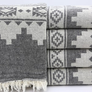 May include: A stack of four gray and white patterned towels with a fringe border. The towels have a geometric design with black and white accents.