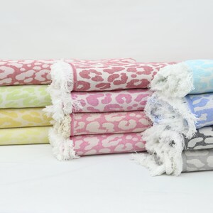 May include: A stack of six colorful towels with a leopard print design. The towels are folded and have a white fringe around the edges.