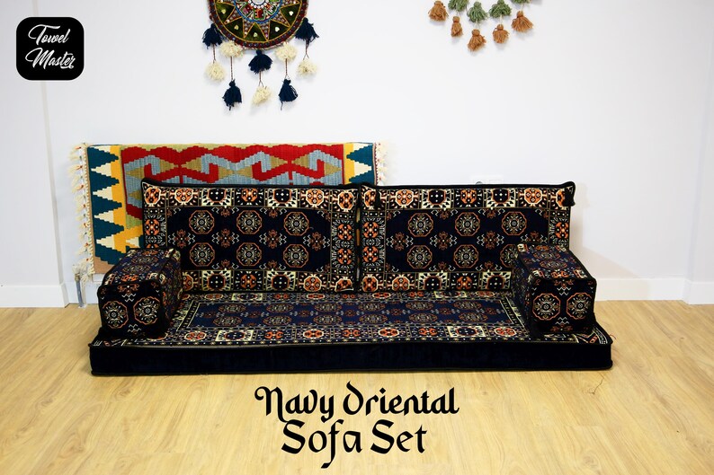 May include: Navy blue floor sofa set with a traditional oriental patterned design. The set includes a large sofa cushion, two smaller cushions, and two armrests. The sofa set is on a wooden floor.