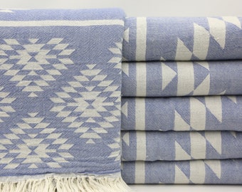 May include: A stack of blue and white patterned towels with a fringe border. The towels are folded and stacked on a white surface.