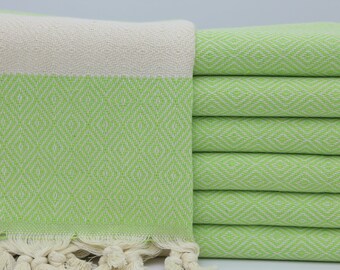 May include: A stack of light green Turkish towels with a white fringe. The towels have a diamond pattern.