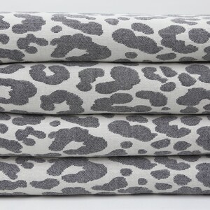 May include: A stack of four gray and white towels with a leopard print pattern. The towels have white fringe around the edges.