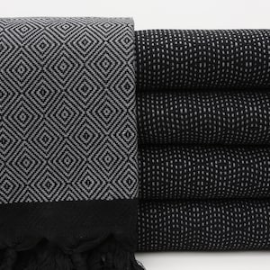 May include: Black and white patterned Turkish towels with fringe. The towels are stacked on top of each other.