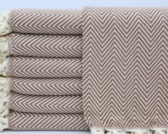 May include: A stack of brown and white chevron patterned towels with white fringe.