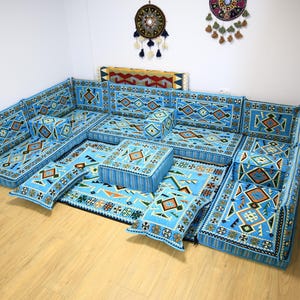 May include: A blue and white patterned floor seating set with a variety of cushions and a small square ottoman. The set is arranged in a U-shape and is perfect for a living room or family room.