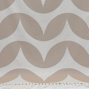 May include: A white and beige patterned throw blanket with fringe on the bottom edge. The pattern is made up of repeating curved shapes.