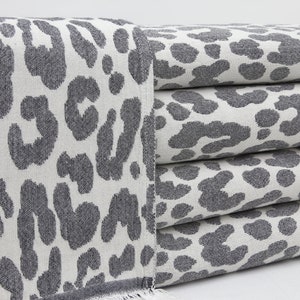 May include: A stack of gray and white towels with a leopard print pattern.