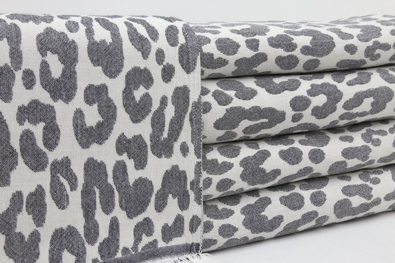 May include: A stack of gray and white towels with a leopard print pattern.