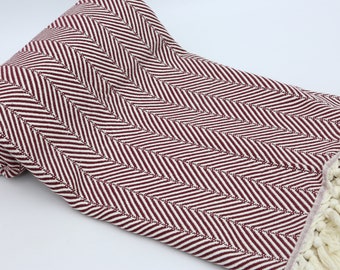 May include: A burgundy and white striped throw blanket with a fringe border. The blanket is made of cotton and is soft and comfortable.