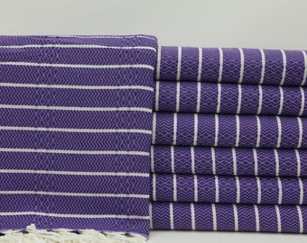 May include: A stack of purple and white striped towels with a fringe border. The towels are made of cotton and are soft and absorbent.