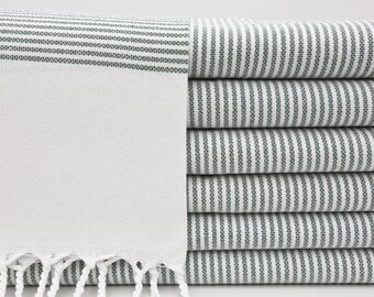 May include: A stack of white towels with green stripes. The towels have a fringe on the bottom.