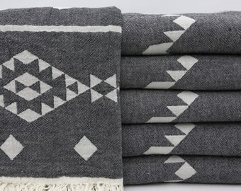 Peut inclure: Une pile de six serviettes turques à franges, à motifs gris et blancs. Les serviettes ont un motif géométrique avec des triangles et des diamants blancs sur un fond gris.