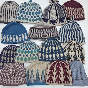 Op de afbeelding: Een collectie van vijftien handgebreide mutsen met diverse patronen, waaronder vissen, geometrische vormen en boommotieven in kleuren zoals blauw, crème, bordeaux en grijs. Elke muts heeft een uniek breipatroon en een ronde vorm.