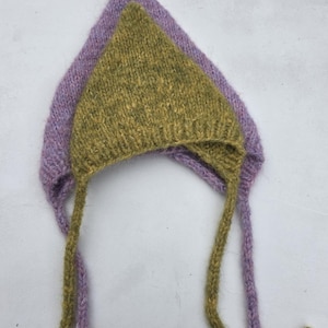 May include: Two knitted baby bonnets. The top bonnet is olive green, and the bottom bonnet is lavender. Both bonnets have long ties. The bonnets are made of a soft, textured yarn. The bonnets are triangular in shape.