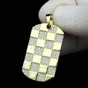 May include: A gold-tone dog tag pendant with a checkerboard pattern of clear cubic zirconia stones.