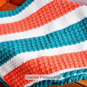 May include: A crochet blanket with a striped pattern in coral, white, and teal. The blanket has a crocheted border. The text "Crochet Pattern PDF" is visible in the image.