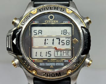 May include: A Citizen Diver's watch with a black rubber strap and a silver-tone case. The digital display shows the time, date, and temperature. The watch has gold-tone accents and is water-resistant to 200 metres.