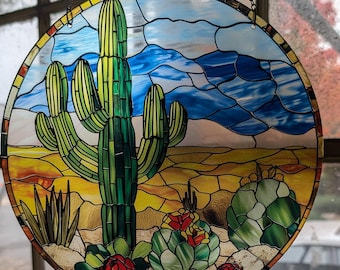 Könnte beinhalten: Ein hängendes Buntglasfenster mit einer Darstellung einer Wüstenlandschaft mit einem großen grünen Kaktus in der Mitte, umgeben von kleineren Kakteen und Blumen. Der Hintergrund ist ein blauer Himmel mit weißen Wolken.