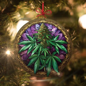 May include: A round Christmas ornament with a stained glass design featuring a green marijuana plant with purple and gold accents.