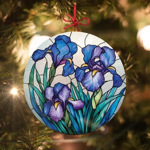Könnte beinhalten: Ein runder Glas-Anhänger mit einem Buntglas-Design aus blauen und violetten Iris-Blumen mit grünen Blättern.