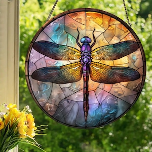 May include: A stained glass window hanging features a colorful dragonfly with purple, blue, yellow, and orange accents. The dragonfly is set against a background of stained glass with a variety of colors and patterns.