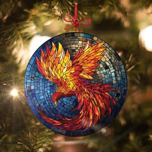 May include: A round glass bauble featuring a mosaic design of a red, orange and yellow phoenix bird with blue and purple accents.