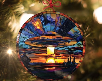 May include: A round stained glass ornament depicting a UFO flying over a sunset landscape. The UFO is blue, yellow, and orange, and the sunset is red, orange, and yellow. The ornament is perfect for adding a touch of whimsy to your holiday decor.