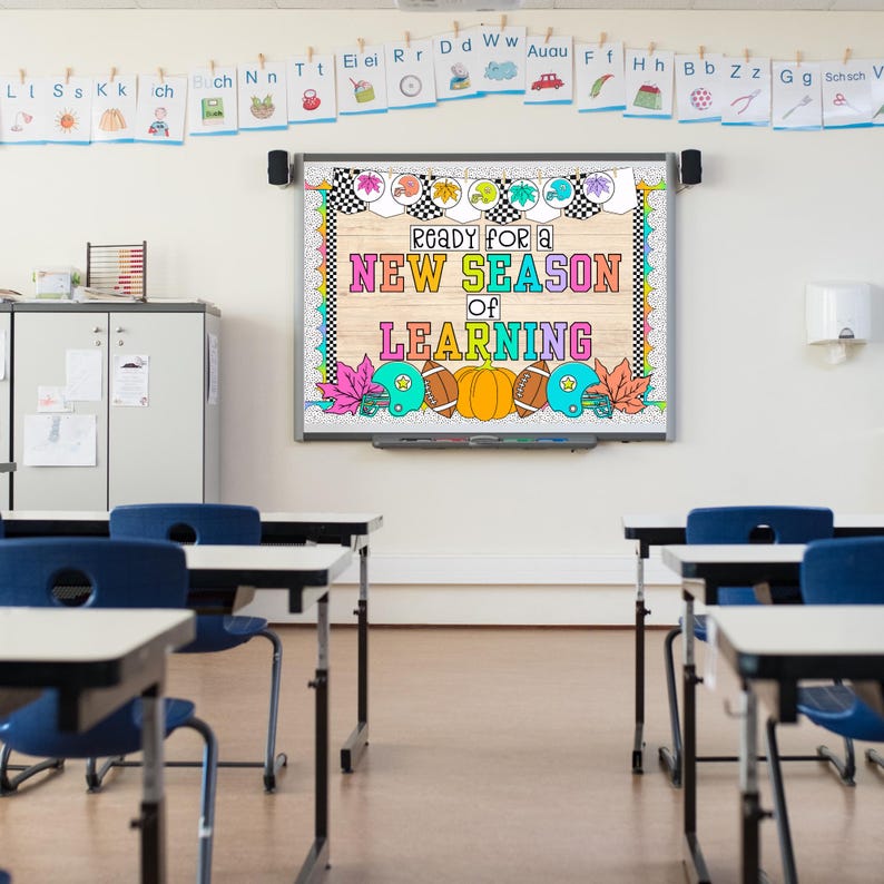 Puede incluir: Un tablero de anuncios de clase con un cartel colorido que dice "Listo para una nueva temporada de aprendizaje". El cartel presenta gr&aacute;ficos de tem&aacute;tica oto&ntilde;al, incluyendo hojas, calabazas y balones de f&uacute;tbol. Tambi&eacute;n hay varios escritorios y sillas en el aula.