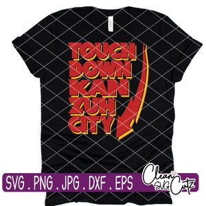 Op de afbeelding: Zwart T-shirt met de tekst "TOUCH DOWN KAN ZUH CITY" in rood en geel. Een rode en gele pijl wijst naar beneden. De onderkant van het shirt heeft de woorden "SVG . PNG . JPG . DXF . EPS" in een paarse rechthoek.