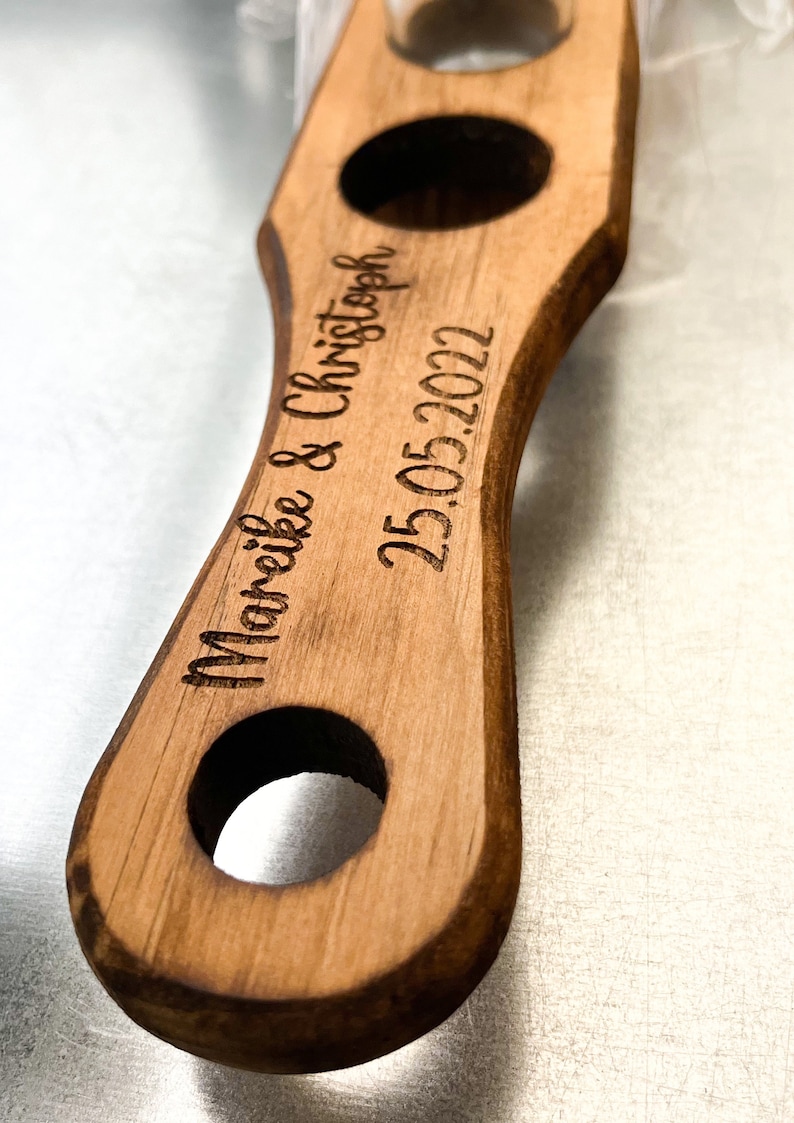 Pode incluir: Uma bandeja de servir de madeira com tr&ecirc;s recortes redondos. A bandeja &eacute; gravada com o texto "Mareike & Christoph 25.05.2022".