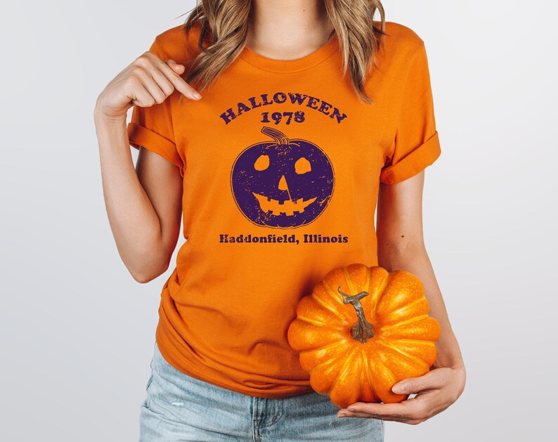 May include: Orange t-shirt with a purple pumpkin graphic and the text "Halloween 1978 Haddonfield, Illinois".