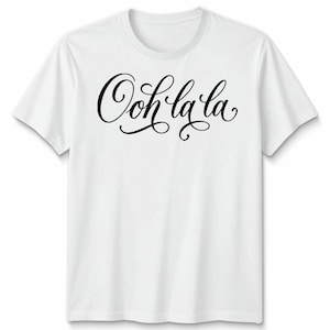 May include: A white t-shirt featuring the phrase "Ooh la la" in black cursive lettering. The text is the focal point, displayed prominently across the chest. The shirt has a classic crew neck and short sleeves, suitable for everyday wear.