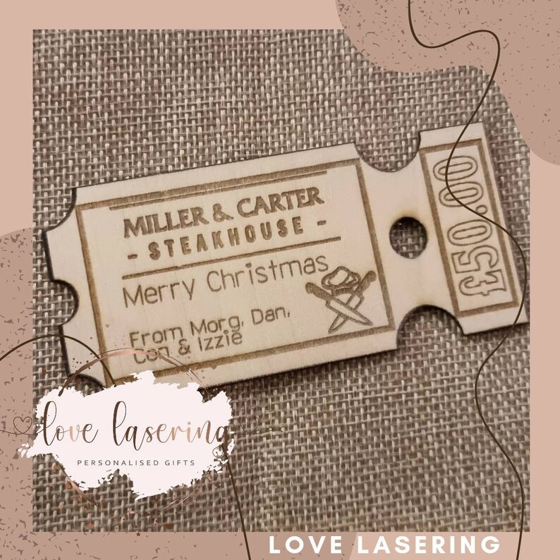 May include: A wooden gift tag shaped like a ticket with the text "MILLER & CARTER - STEAKHOUSE - Merry Christmas From Morg. Dan, Con & Izzie" and the number "&pound;50.00" printed on it.