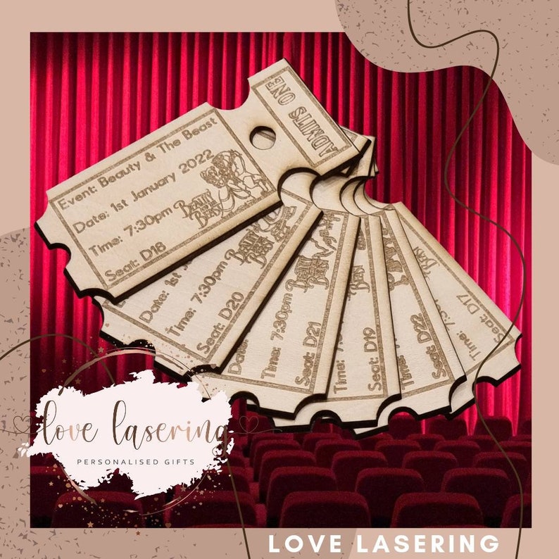 May include: A set of six wooden movie ticket stubs with the text "ADMITS ONE" and "Beauty & The Beast" printed on them. The tickets are arranged in a fan shape and are set against a red velvet curtain backdrop.
