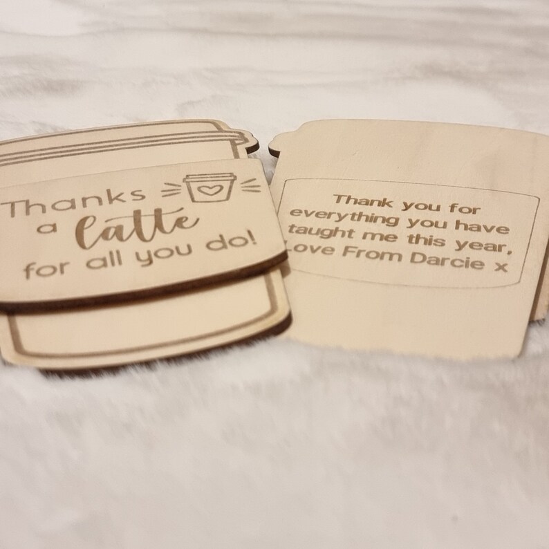 May include: Two wooden coffee cup shaped signs with a thank you message. The first sign says "Thanks a latte for all you do!" with a small heart inside the cup. The second sign says "Thank you for everything you have taught me this year, Love From Darcie x".