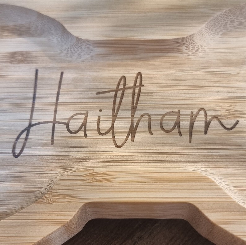 May include: A light brown wooden serving tray with the name "Haitham" engraved on the surface.