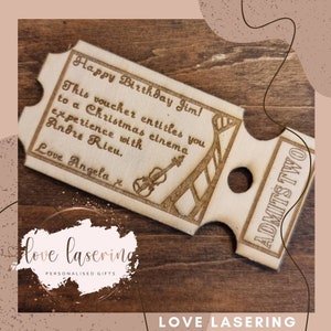 May include: A wooden ticket with the text "Happy Birthday Jim! This voucher entitles you to a Christmas cinema experience with Andre Rieu. Love Angela" and a small illustration of a violin. The ticket is labeled "ADMITS TWO".