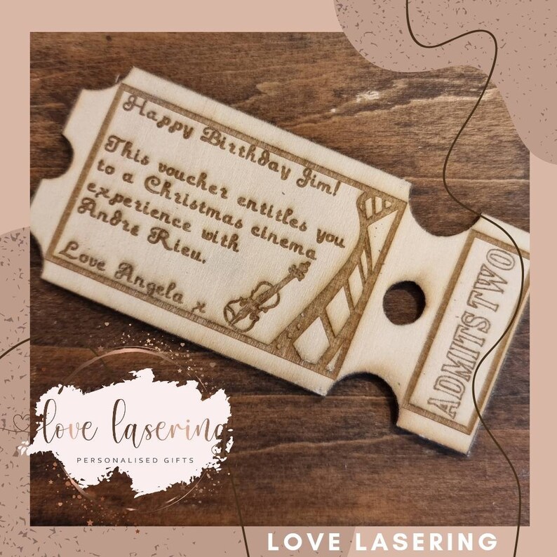 May include: A wooden ticket with the text "Happy Birthday Jim! This voucher entitles you to a Christmas cinema experience with Andre Rieu. Love Angela" and a small illustration of a violin. The ticket is labeled "ADMITS TWO".