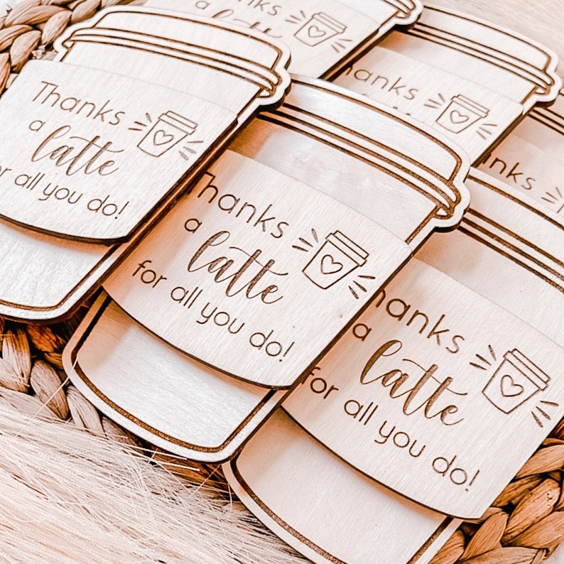 May include: Set of six wooden coffee cup shaped tags with the text "Thanks a latte for all you do!" and a small coffee cup icon. The tags are light brown and have a natural wood grain.
