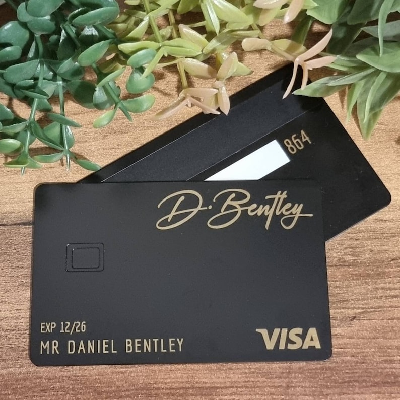 Pu&ograve; includere: Carta di credito nera con lettere dorate. La carta ha il nome "D. Bentley" e il testo "EXP 12/26 MR DANIEL BENTLEY VISA".