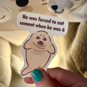 May include: A sticker with a cartoon seal and the text "He was forced to eat cement when he was 6".