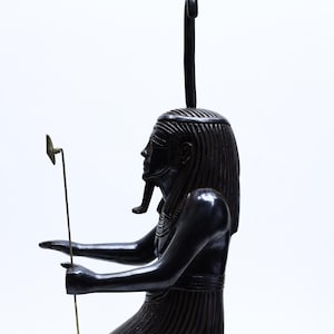 Op de afbeelding: Zwart knielend beeld van een Egyptische farao met een gouden staf en hiërogliefen op de basis.