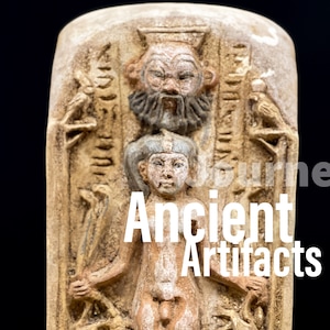 May include: A close-up of an ancient Egyptian artifact, a stone tablet with a relief carving of a bearded god and a young pharaoh. The tablet is made of a light brown stone and has hieroglyphic inscriptions.