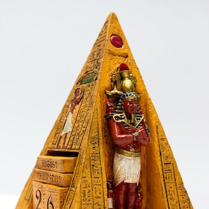 May include: A gold pyramid-shaped calendar with an Egyptian pharaoh figure inside. The calendar has a date display showing August 26th, Thursday.
