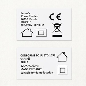 Puede incluir: Dos etiquetas rectangulares blancas con texto y s&iacute;mbolos negros. La etiqueta superior incluye el texto "feutre&ouml;", la direcci&oacute;n, el voltaje y una marca CE. La etiqueta inferior indica "CONFORMS TO UL STD 1598", "feutre&ouml;", "BULLE", el voltaje y "MADE IN FRANCE".