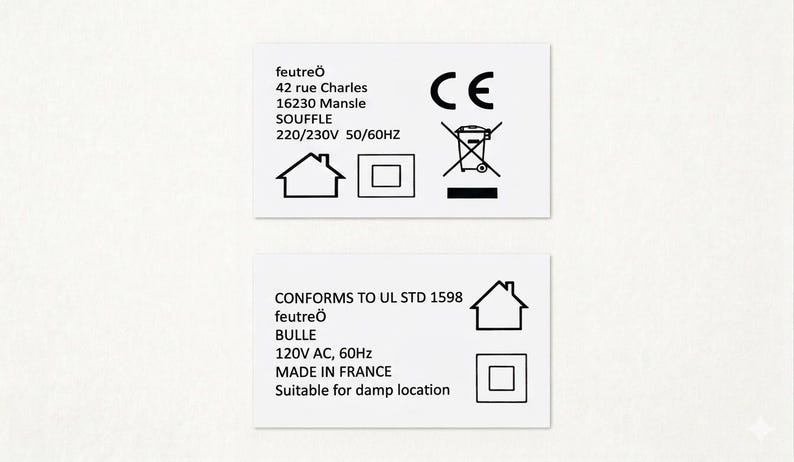 Puede incluir: Dos etiquetas rectangulares blancas con texto y s&iacute;mbolos negros. La etiqueta superior incluye el texto "feutre&ouml;", la direcci&oacute;n, el voltaje y una marca CE. La etiqueta inferior indica "CONFORMS TO UL STD 1598", "feutre&ouml;", "BULLE", el voltaje y "MADE IN FRANCE".
