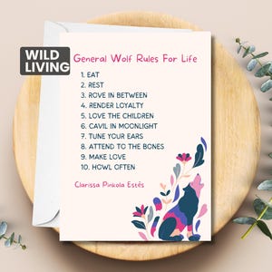May include: A cream-colored card with the text "General Wolf Rules For Life" and a howling wolf illustration. The card is on a wooden plate with eucalyptus sprigs. The text includes rules such as "Eat", "Rest", and "Howl Often".